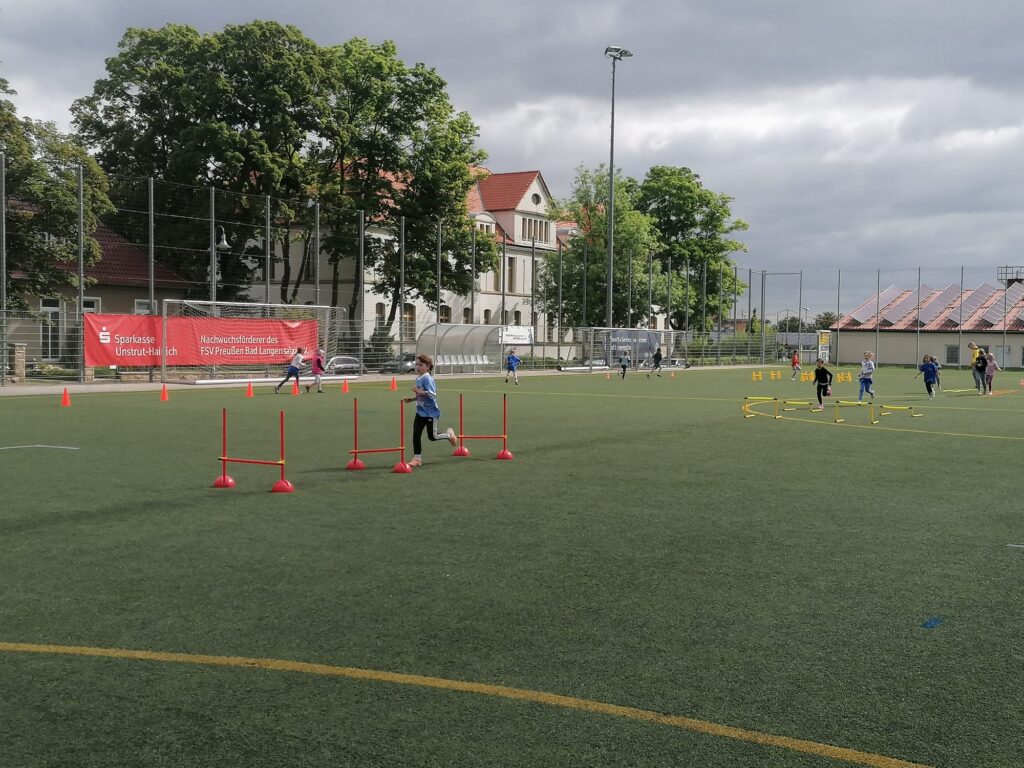 Ein junge rennt Slalom auf einen Fußballfeld.