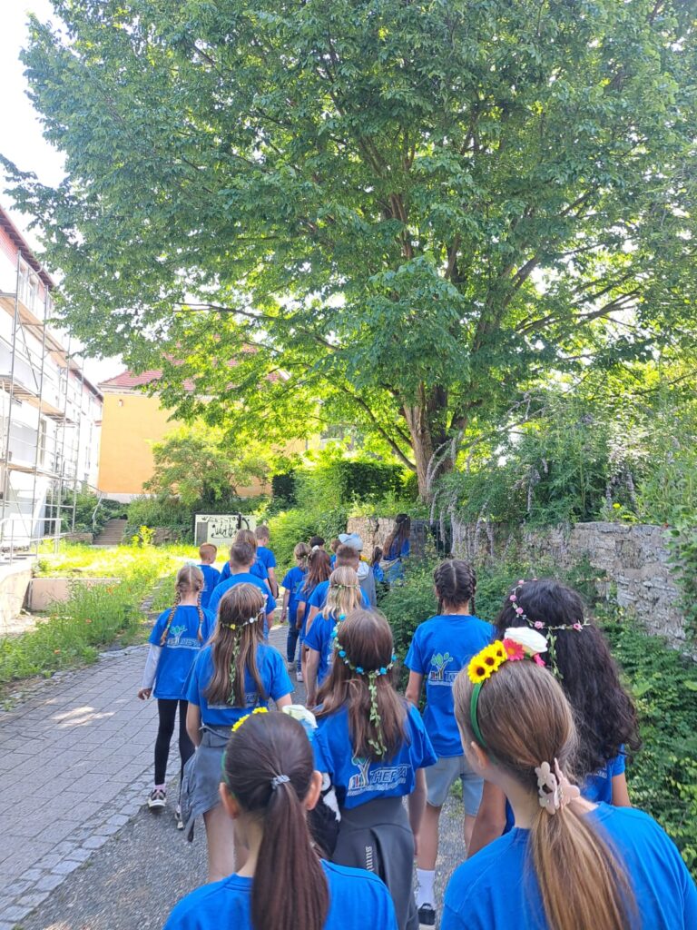 Kinder die mit blauen THEPRA T-Shirt in einer großen Gruppe laufen.