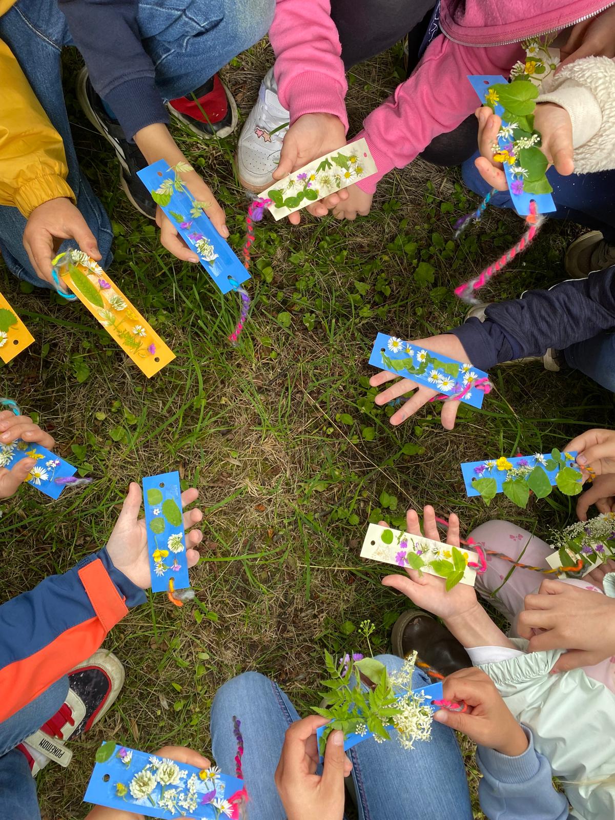 Kinder zeigen Blätter und Blüten die sie gefunden haben.