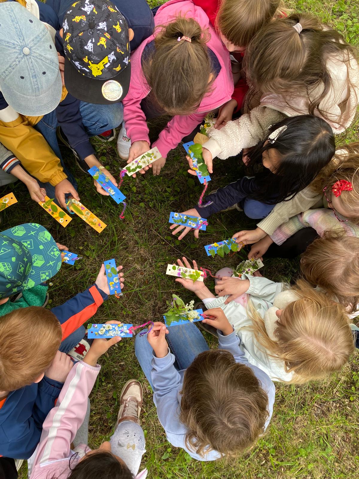 Kinder sitzen im Kreis und zeigen Blätter die sie von Bäumen gefunden haben.