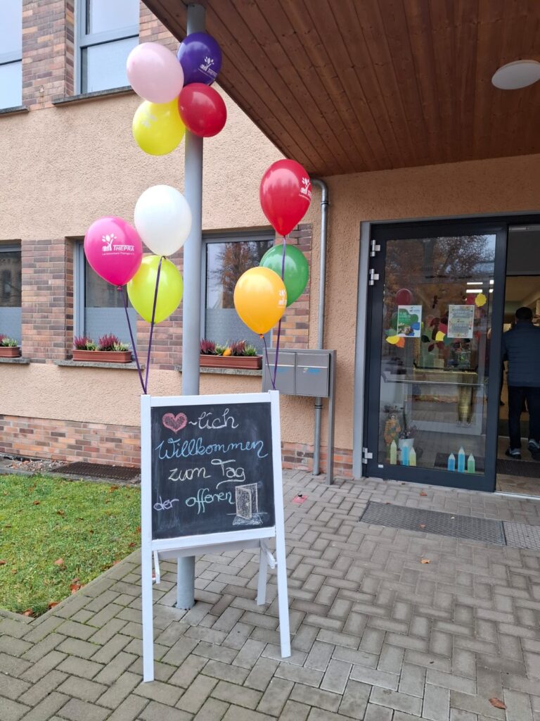 Eingang der Schule mit einem Schild auf dem steht: " Herzlich Willkommen zum Tag der offenen Tür"